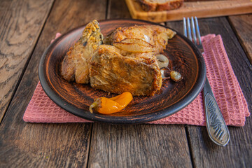 Fried fish with onions, yellow pickled peppers. Kitchen napkin and fork.