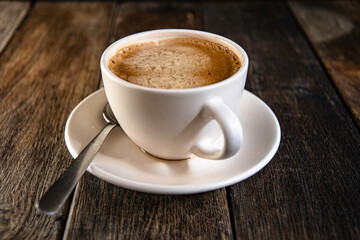 A cup of coffee on a saucer, on a wooden background.
