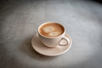 Cup of coffee on a saucer on a gray background.