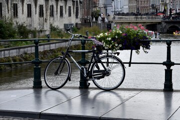 Fototapeta na wymiar Bicycle parked over a canal next to flowers in Ghent