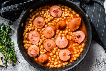 Beans with sausages in tomato sauce in a pan. White background. Top view
