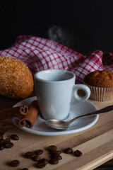 Aromatic coffee with cinnamon sticks, coffee beans and donut and smoke on a wooden background. Coffee break.