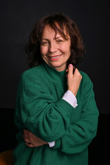 Adult brunette woman in a green sweater in the studio. Beautiful Model Age. Modern fashion for appearance. Copy space