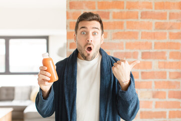 handsome man looking astonished in disbelief, pointing at object on the side and saying wow,...