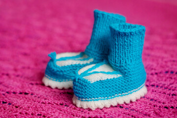Small white-blue children's knitted booties, hand-knitted, on a wool background