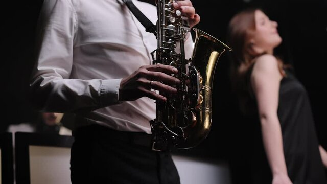Saxophonist play on golden saxophone. Live performance. Jazz music. Cool saxophone player performing a solo on stage. Musician playing in band.