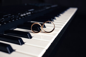 Two wedding rings on a piano with dark background