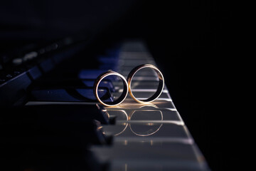 Two wedding rings on a piano with dark background