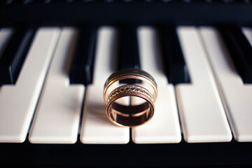Two wedding rings on a piano with dark background