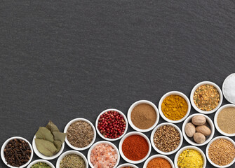 Assorted seasonings and herbs over stone background with copy space