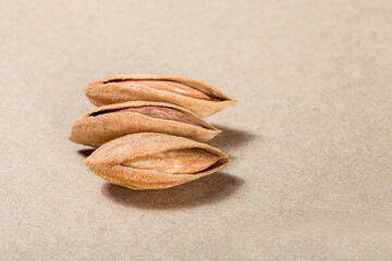 Fototapeta na wymiar dried almonds in shell with cracked protein food on brown paper texture close-up.