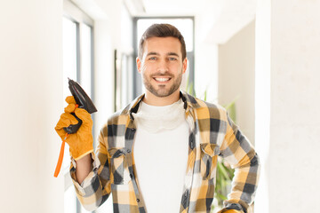 handyman smiling happily with a hand on hip and confident, positive, proud and friendly attitude