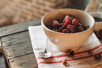 Delicious and healthy breakfast with raspberries. Morning aesthetics and beautiful layout on a wooden table. Granola for healthy breakfast.