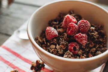 Delicious and healthy breakfast with raspberries. Morning aesthetics and beautiful layout on a wooden table. Granola for healthy breakfast.