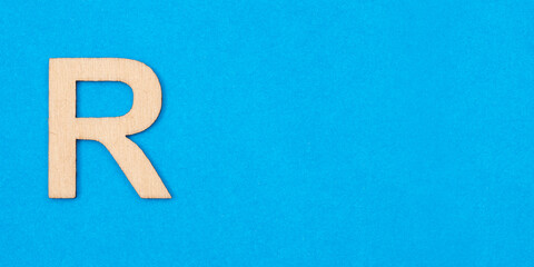 Letter R in wood on blue background