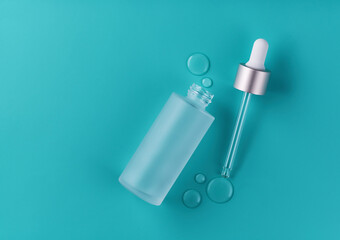 glass vial with professional facial serum on a blue background, top view.