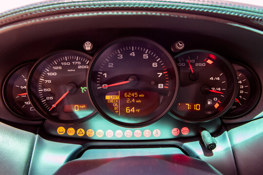 Sports car cockpit shows gauges with all warning lights illuminated on the speedometer.