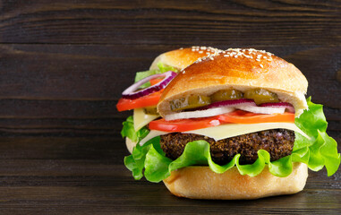 Cheeseburger on a wooden background. Hamburger with cheese. Burger isolated. Tasty dinner. Copy space