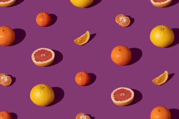 Fototapeta na wymiar Summer fresh fruit pattern on purple background. Vivid colors of grapefruit and oranges.