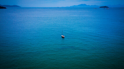 Fototapeta premium A sailboat navigates in the limpid waters of the Angra dos Reis bay, Rio de Janeiro - Brazil