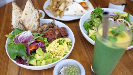 Top view of vegan lunch of two buddha bowls, wraps, appetizers and a green smoothie served on a table