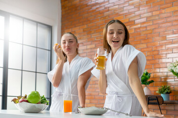 Selective Focus on cheerful girl in white bathrobe drinking fresh fruit juice for a healthy diet after exercise workout at the home in the morning. Concept of clean eating lifestyle, vegetarian food