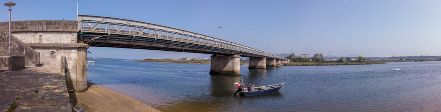 Fao, Esposende, Portugal - April 3, 2021: Panoramic of Fao metallic bridge, known as D. Lu&iacute;s Filipe Bridge. It is located at Fao in Braga District, crossing the C&aacute;vado River. The riverside promenade.