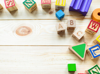 Wooden kids cubes ABC on wooden table. Educational toys blocks, pyramid, pencils, numbers. Toys for kindergarten, preschool or daycare. Copy space for text. Top view	
