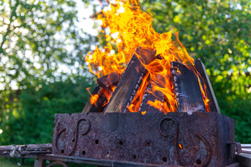A large fire made of planks. Firewood in a bright flame. Firewood burns brightly in an iron grill.