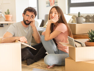 young couple feeling bored, frustrated and sleepy after a tiresome, dull and tedious task, holding...