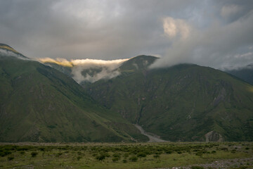 green mountains with mining roads that are among the clouds