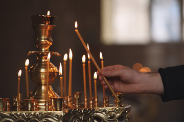 Man lighting candle near stand in church, closeup. Baptism ceremony