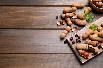 Delicious ripe tamarinds on wooden table, flat lay. Space for text