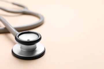 Stethoscope on beige background, closeup. Space for text