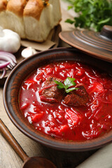 Stylish brown clay bowl with Ukrainian borsch served on wooden table