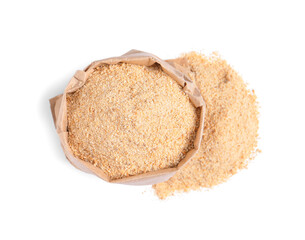 Fresh bread crumbs and paper bag on white background, top view
