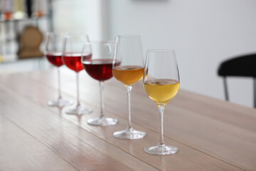 Different sorts of wine in glasses prepared for tasting on wooden table indoors