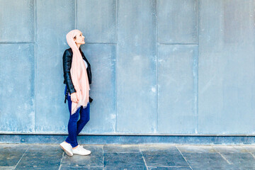 Woman in profile leaning against a wall with space for copy looking up pink partner on the head in...