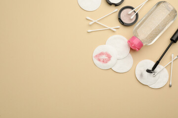 Dirty cotton pads, swabs, cosmetic products and micellar cleansing water on beige background, flat lay. Space for text
