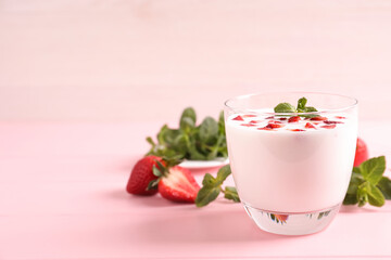Delicious drink with strawberries on pink table, space for text