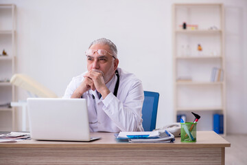 Fototapeta premium Old male doctor working in the clinic