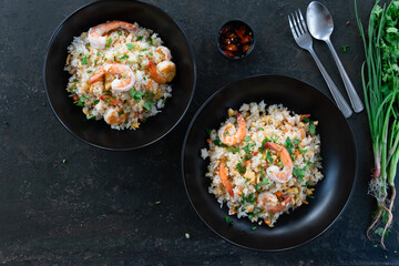 Asian fried rice with shrimp on the black dish in Thai. Prepared in wok. Top view.