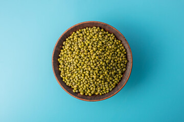 Bowl of raw Asian beans on a blue background. Concept of a balanced diet and healthy food. Top view