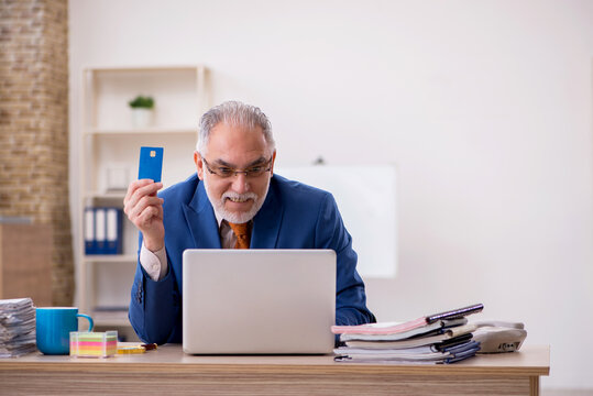 Old businessman employee holding credit card in the office
