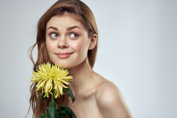 Portrait of a beautiful woman with a yellow flower on a light background cropped with Copy Space Model