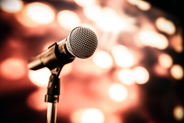 Fototapeta na wymiar Public speaking backgrounds, Close-up the microphone on stand for speaker speech presentation stage performance with blur and bokeh light background.