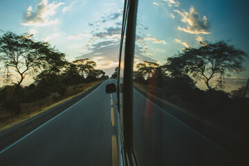Reflections of the sunset on the road through the window of the moving car