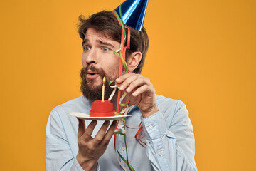 Birthday boy in a cap with a birthday cake in his hand and a candle