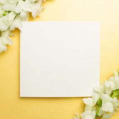 White memo pad with snapdragon flowers on yellow background. flat lay, top view, copy space