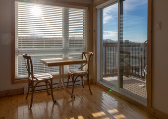 vue d'une table et deux chaises en bois devant une fenêtre avec des stores horizontaux